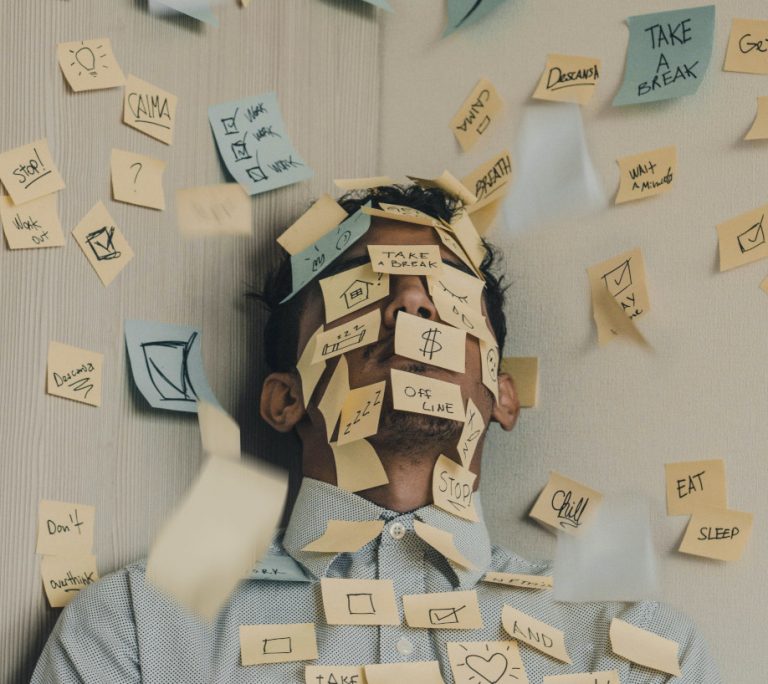 A very stressed business man with post-its stuck to his face practices stress management